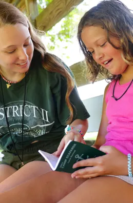 Counselor and camper with green book