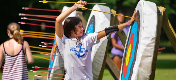 girl pulling arrow out of target