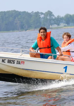 Two campers and a counselor on a motorboat