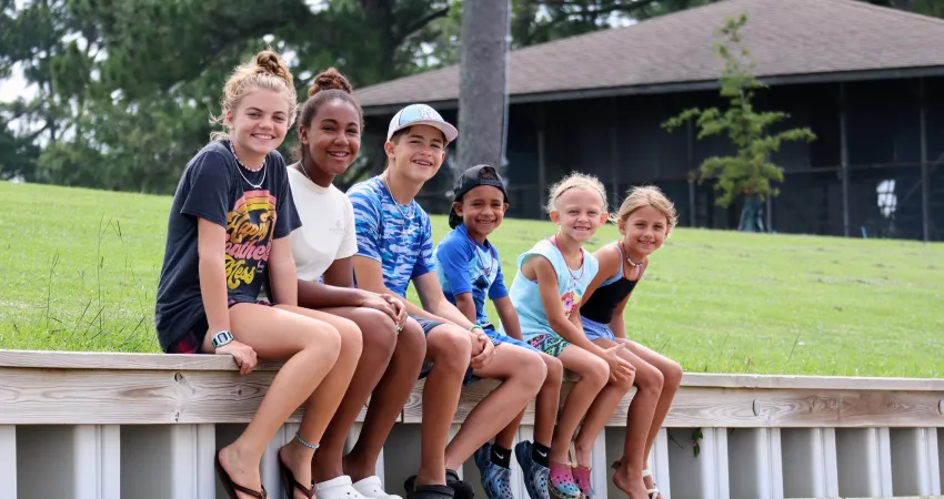 Mix of kids sitting on the dock during day camp