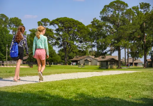 Two girls walking on path toward a cabin