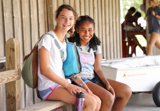 Two girls waiting outside dining on a bench