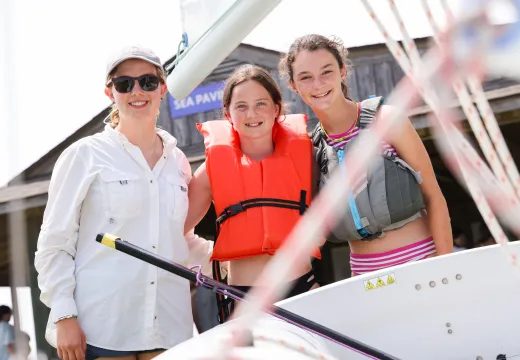 Counselor and two girls setting out to sail